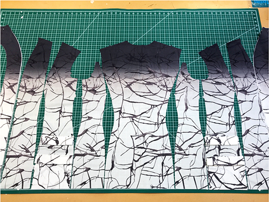 9 pattern pieces cut out in fabric and laid out next to each other with the dark plum ombre transition line even all the way across. 