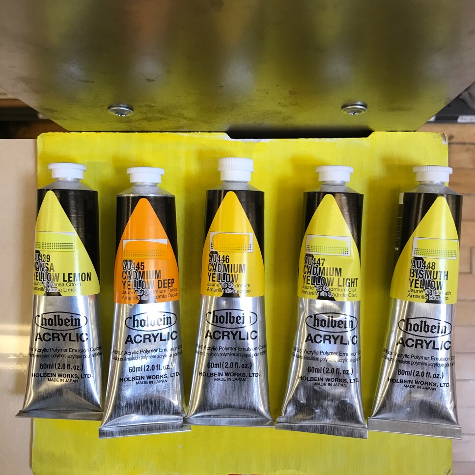 Tubes of Holbein Acrylic paint in 5 different colors of yellow. 