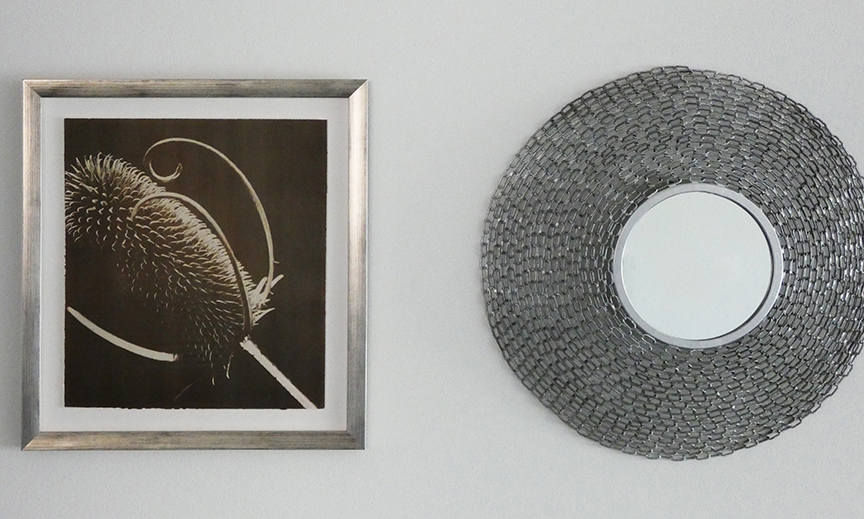 Framed teasel print next to a round mirror framed with concentric circles of silver chain