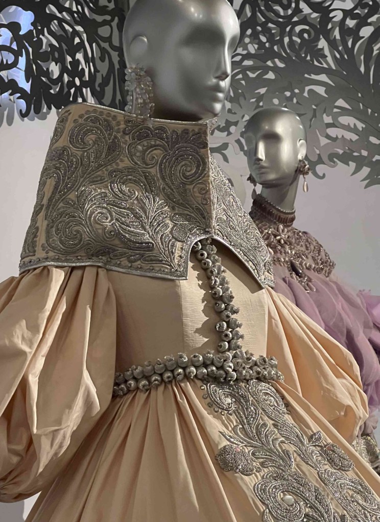 sliver mannequin bust with a very high and wide collar looking to the right