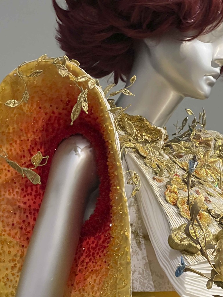 partial view of burgundy haired mannequin bust and dress sleeve detail